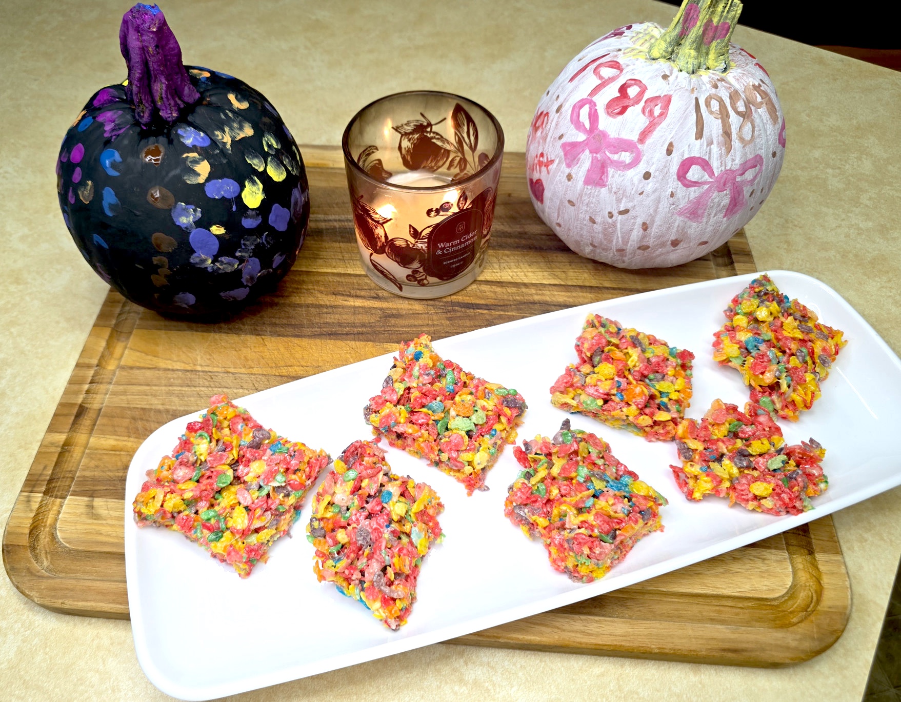 Fruity Pebbles marshmallow treats on a platter with painted pumpkins