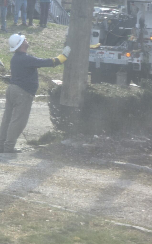 Lineman guiding a utility pole into place near a bucket truck
